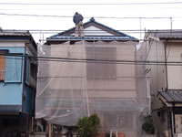 瓦屋根からシート養生をする職人