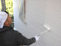 コーキング補修後の壁に塗装をする職人