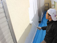 2階ベランダの壁を塗装する職人
