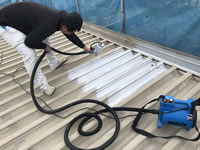 折半屋根の吹き付け塗装をする職人