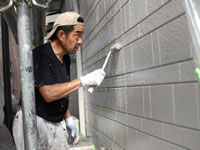 ローラーで外壁に上塗りをかける職人
