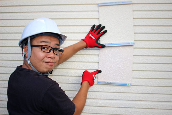 屋外で実際の壁に色サンプルをあてて検討